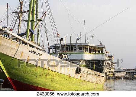 Stock Photograph - Pinisi, a traditional two masted wooden cargo sailing ship moored in Sunda Kelapa Harbour, Jakarta, Java Island, Indonesia. Fotosearch