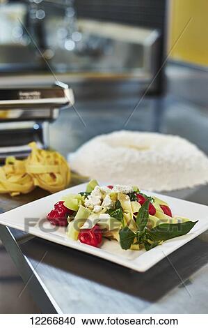 Stock Image - Plate of freshly made pasta with roasted red peppers, basil, and goat cheese; Ontario, Canada. Fotosearch