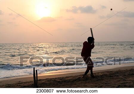 Stock Photo - Playing cricket, the national sport of India, on Anjuna Beach at sunset, Goa State, India, Asia.. Fotosearch