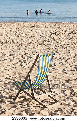 Stock Image - Playing In Water And Deck Chair On Beach On A Sunny Spring Day At Bournemouth Beach; Bournemouth, Dorset, England, Uk. Fotosearch