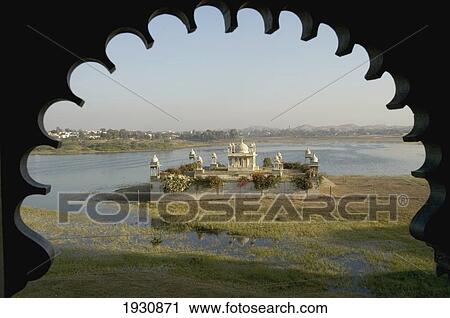 Stock Image - Pleasure palace on lake seen from scalloped arch in Udai Bilas Palace hotel, Dungarpur, Rajasthan, India, Dungarpur, Rajasthan, India.. Fotosearch