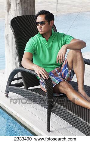 Portait of a man sitting in a deck chair by the pool; Honolulu, Oahu, Hawaii, United States of America View Large Photo Image Stock Image - Portait of a man sitting in a deck chair by the pool; Honolulu, Oahu, Hawaii, United States of America. Fotosearch