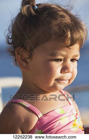 Portrait of a baby girl in a bathing suit with sand on her shoulders, playing on the beach; Poipu, Kauai, Hawaii, United States of America View Large Photo Image Stock Photo - Portrait of a baby girl in a bathing suit with sand on her shoulders, playing on the beach; Poipu, Kauai, Hawaii, United States of America. Fotosearch