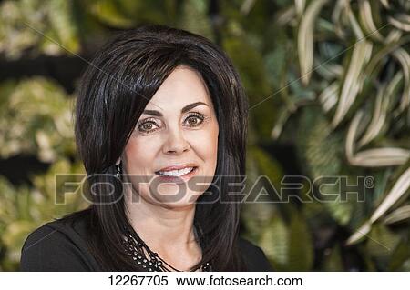 Stock Photography - Portrait of a businesswoman against a living wall; Edmonton, Alberta, Canada. Fotosearch