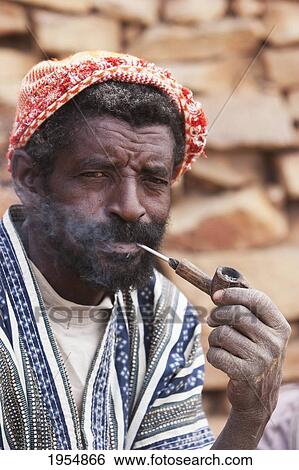 Stock Photograph - Portrait of a Dogon man smoking a pipe in Tireli, Mali. Fotosearch