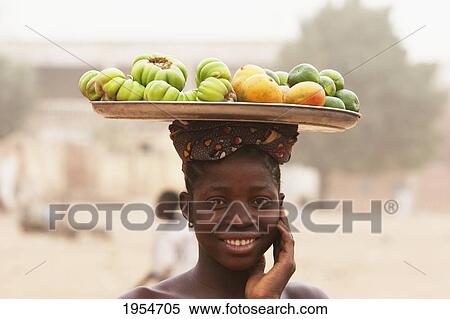 Stock Photography - Portrait of a girl carrying fruits on her head in Segou, Mali. Fotosearch