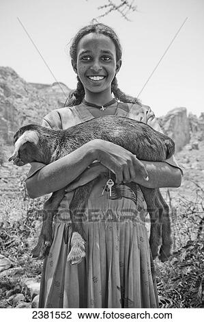 Stock Image - Portrait of a girl holding a goat; Ethiopia. Fotosearch