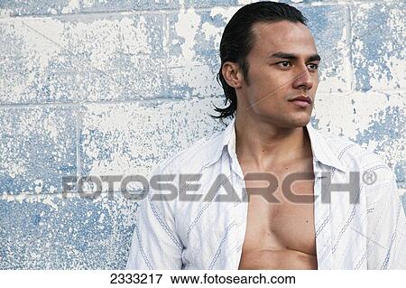 Portrait of a man with shirt unbuttoned, leaning against blue wall; Honolulu, Oahu, Hawaii, United States of America View Large Photo Image Stock Photo - Portrait of a man with shirt unbuttoned, leaning against blue wall; Honolulu, Oahu, Hawaii, United States of America. Fotosearch
