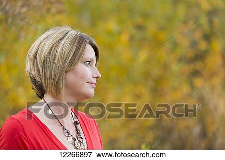 Stock Photo - Portrait of a mature woman in a park in autumn; Edmonton, Alberta, Canada. Fotosearch
