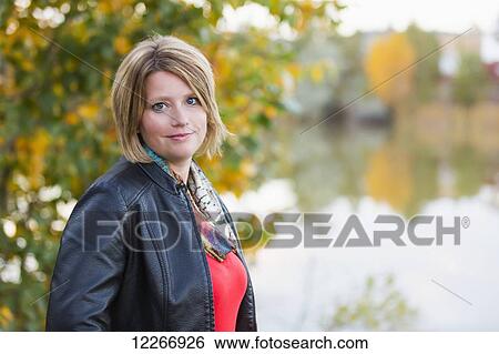 Stock Photograph - Portrait of a mature woman in a park in autumn; Edmonton, Alberta, Canada. Fotosearch