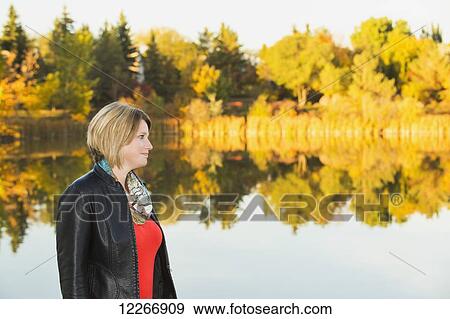 Stock Photo - Portrait of a mature woman in a park beside a lake in autumn; Edmonton, Alberta, Canada. Fotosearch