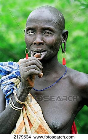 Portrait of a Mursi tribal woman with her lower lip pierced to hold a traditional 'debhi a tugoin' (lip plate). Makki / South Omo / Southern Nations, Nationalities & People's Region (Ethiopia). View Large Photo Image Picture - Portrait of a Mursi tribal woman with her lower lip pierced to hold a traditional 'debhi a tugoin' (lip plate). Makki / South Omo / Southern Nations, Nationalities & People's Region (Ethiopia).. Fotosearch