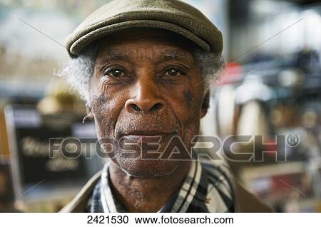 Stock Image - Portrait of a senior man wearing a cap; London, England. Fotosearch