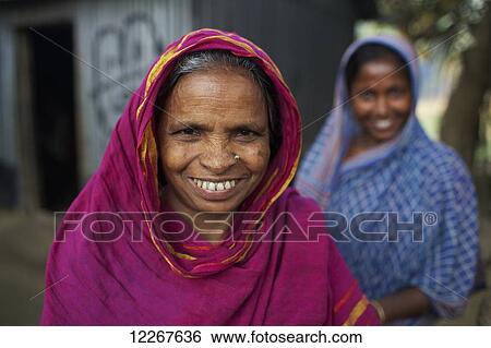 Stock Photograph - Portrait of a senior woman with daughter in background; Kishoreganj, Bangladesh. Fotosearch