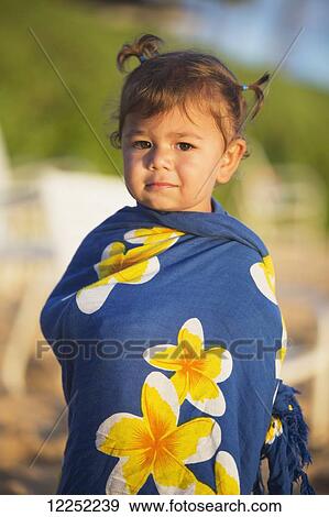 Stock Photo - Portrait of a toddler girl wrapped in a tropical sarong on the beach; Poipu, Kauai, Hawaii, United States of America. Fotosearch