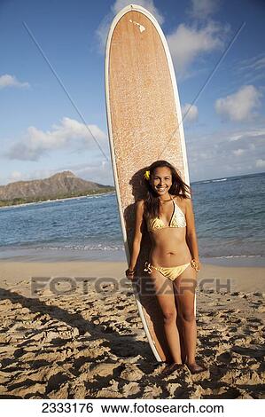 Portrait of a woman on a beach in a bikini holding a surfboard; Waikiki, Oahu, Hawaii, United States of America View Large Photo Image Stock Photograph - Portrait of a woman on a beach in a bikini holding a surfboard; Waikiki, Oahu, Hawaii, United States of America. Fotosearch