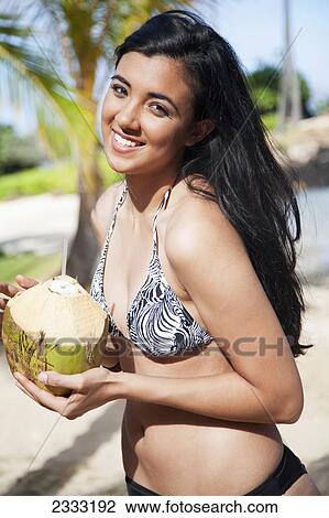 Portrait of a young woman in a bikini on the beach with a fresh coconut to drink; Oahu, Hawaii, United States of America View Large Photo Image Stock Image - Portrait of a young woman in a bikini on the beach with a fresh coconut to drink; Oahu, Hawaii, United States of America. Fotosearch