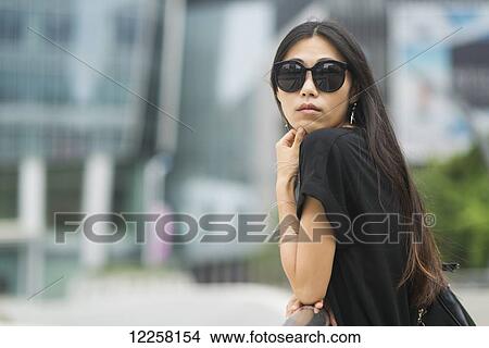 Picture - Portrait of a young woman with long brunette hair and sunglasses; Xiamen, China. Fotosearch