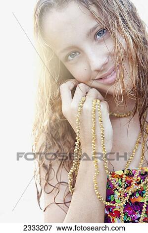 Stock Photo - Portrait of a young woman with long blond hair and a shell lei necklace; Oahu, Hawaii, United States of America. Fotosearch