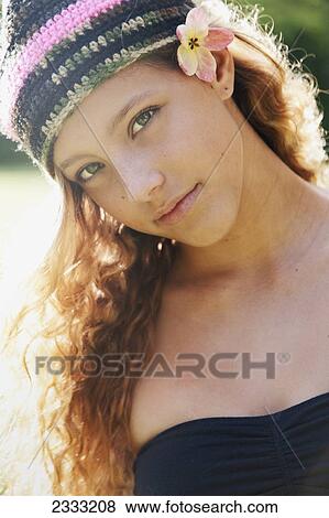 Stock Photo - Portrait of a young woman with long blond hair with a knit hat and tropical flower accessory; Oahu, Hawaii, United States of America. Fotosearch
