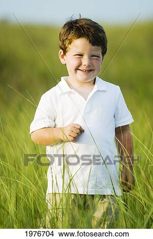 Picture - Portrait Of Cute Young Boy In Field Of Tall Grass.. Fotosearch