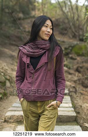 Stock Photo - Portrait of female model walking on a mountain trail; Xiamen, China. Fotosearch