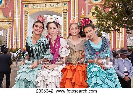 Stock Image - Portrait Of Four Young Women Wearing Traditional Dresses During April Feria Festival; Seville, Andalucia, Spain. Fotosearch