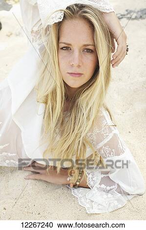 Stock Image - Portrait of young woman laying in the sand; Kauai, Hawaii, United States of America. Fotosearch