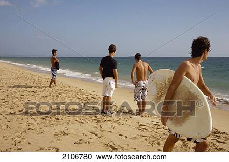 Stock Image - Portugal, Young men with surfing boards on Estoril beach; Lisbon. Fotosearch