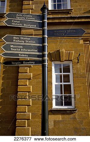 Stock Photo - Post and destination signs for landmarks in front of a building; Banbury, Oxfordshire, England. Fotosearch