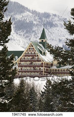 Stock Photography - Prince Of Wales Hotel In The Winter Framed By Evergreen Trees And Snow Covered Mountains; Waterton Alberta Canada. Fotosearch