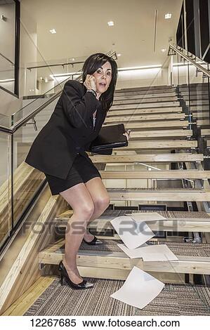 Stock Photography - Professional businesswoman drops her papers on stairway and is embarrassed; Edmonton, Alberta, Canada. Fotosearch