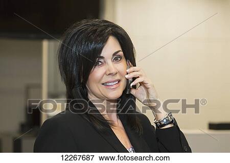 Stock Photo - Professional businesswoman talking on her cell phone; Edmonton, Alberta, Canada. Fotosearch