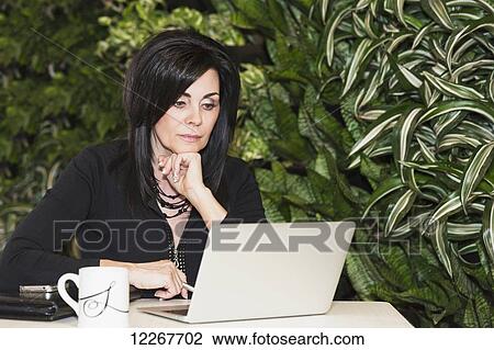 Professional businesswoman working on her laptop computer in cafeteria; Edmonton, Alberta, Canada View Large Photo Image Stock Image - Professional businesswoman working on her laptop computer in cafeteria; Edmonton, Alberta, Canada. Fotosearch
