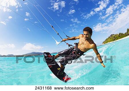 Stock Photo - Professional kiteboarder Andre Philip kitesurfing over the crystal blue waters; Necker Island, British Virgin Islands. Fotosearch
