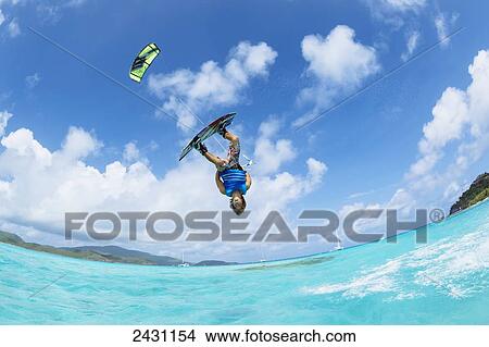 Picture - Professional kiteboarder Jesse Richman kitesurfing over the crystal blue waters; Necker Island, British Virgin Islands. Fotosearch
