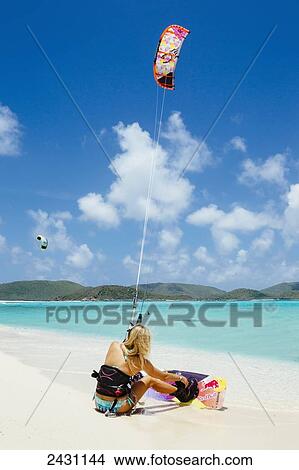 Picture - Professional kiteboarder Susi Mai sitting on the white sand looking at the crystal blue waters; Necker Island, British Virgin Islands. Fotosearch