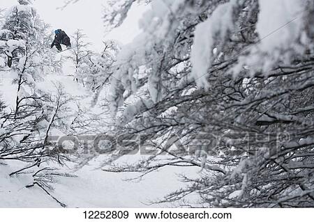 Stock Photo - Professional snowboarder making a jump in fresh snow near Ushuaia, Patagonia, Argentina. Fotosearch