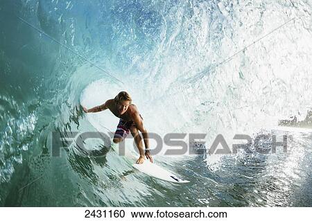 Stock Image - Professional surfer Granger Larson gets barreled on beautiful blue wave; Maui, Hawaii, United States of America. Fotosearch