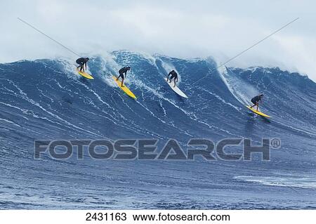 Stock Image - Professional surfers paddling into large waves at the infamous big wave spot know as Jaws or Peahi; Maui, Hawaii, United States of America. Fotosearch