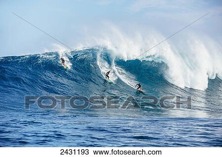 Stock Image - Professional surfers paddling into large waves at the infamous big wave spot know as Jaws or Peahi; Maui, Hawaii, United States of America. Fotosearch