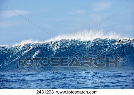 Stock Image - Professional surfers paddling into large waves at the infamous big wave spot know as Jaws or Peahi; Maui, Hawaii, United States of America. Fotosearch