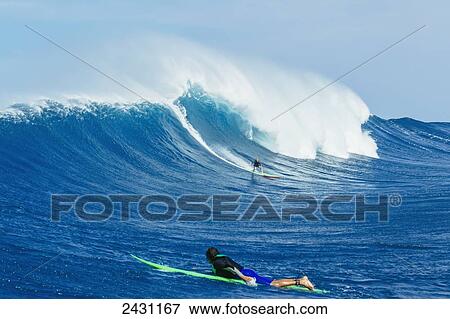Stock Photo - Professional surfers paddling into large waves at the infamous big wave spot know as Jaws or Peahi; Maui, Hawaii, United States of America. Fotosearch