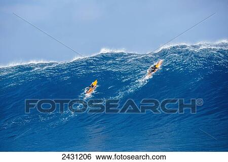 Stock Photograph - Professional surfers paddling into large waves at the infamous big wave spot know as Jaws or Peahi; Maui, Hawaii, United States of America. Fotosearch