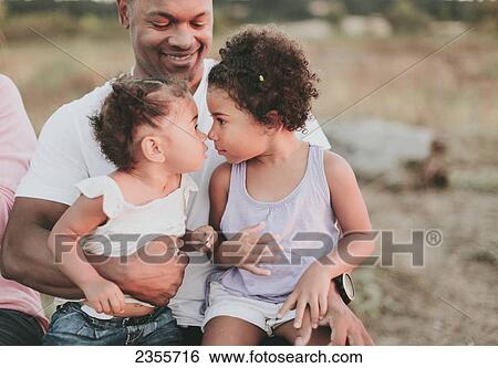 Stock Photograph - Proud Father Embracing Daughters On Beach; British Columbia, Canada. Fotosearch