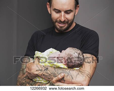 Stock Image - Proud father holding newborn baby girl in delivery room; Edmonton, Alberta, Canada. Fotosearch