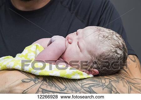 Stock Photo - Proud father holding newborn baby girl in delivery room; Edmonton, Alberta, Canada. Fotosearch