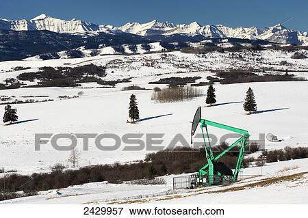 Pumpjack in snow covered field with snow covered mountains in the background and blue sky; Longview, Alberta, Canada View Large Photo Image Stock Photo - Pumpjack in snow covered field with snow covered mountains in the background and blue sky; Longview, Alberta, Canada. Fotosearch