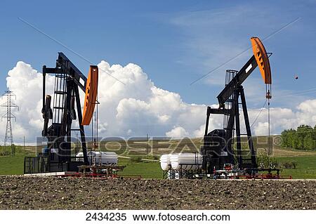 Stock Photography - Pumpjacks with thunderstorm clouds and blue sky in the background; Alberta, Canada. Fotosearch
