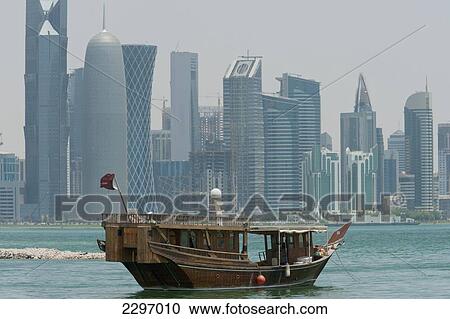 Stock Image - Qatar, Wooden boat in front of modern city skyline; Doha. Fotosearch
